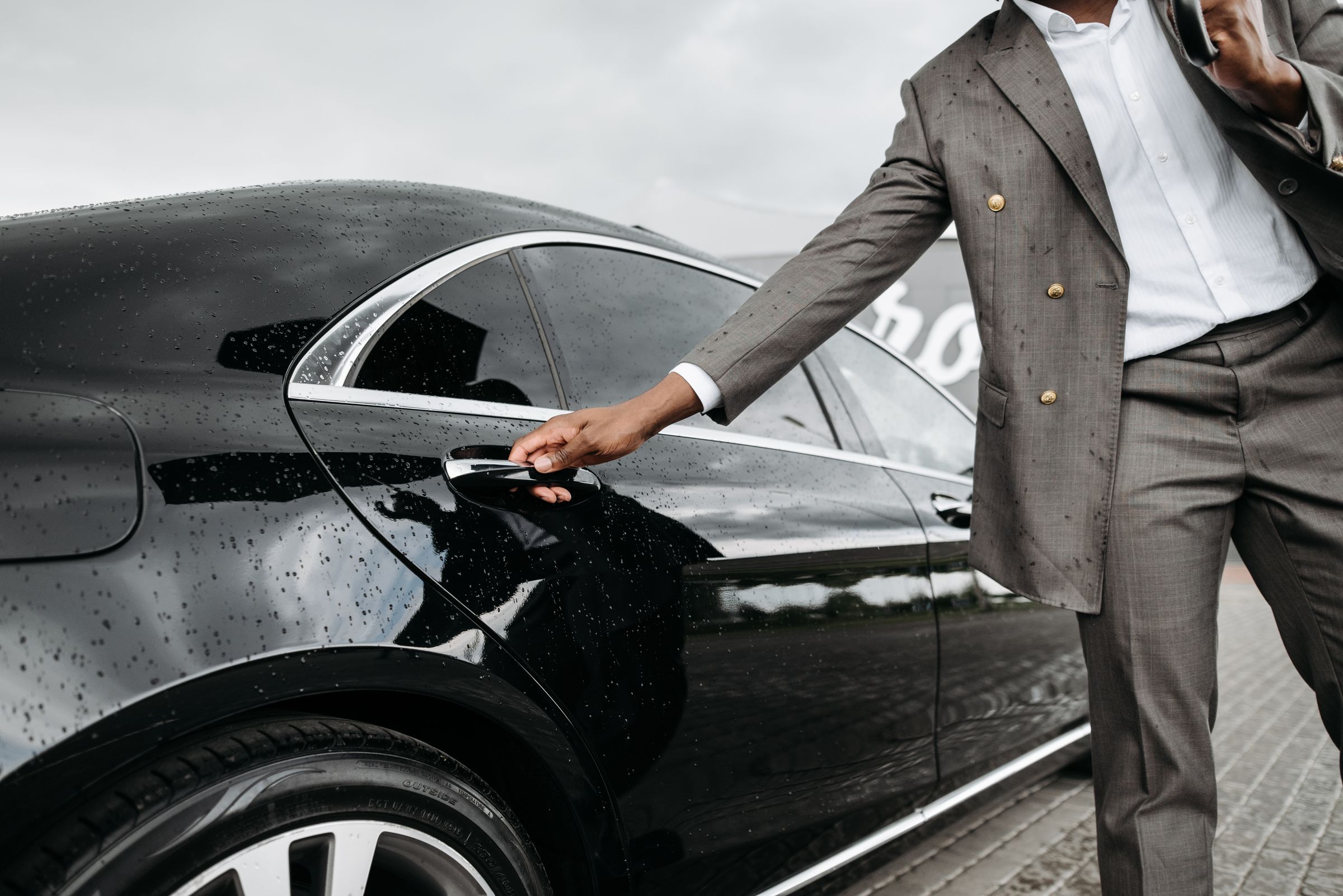 Professional chauffeur opening a luxury sedan door